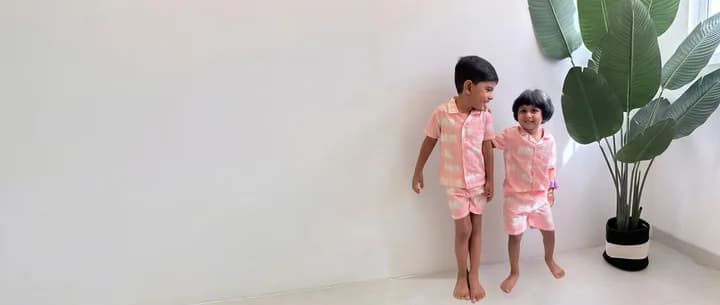 Children in colourful Tiny Tusk outfits beside a tall green plant