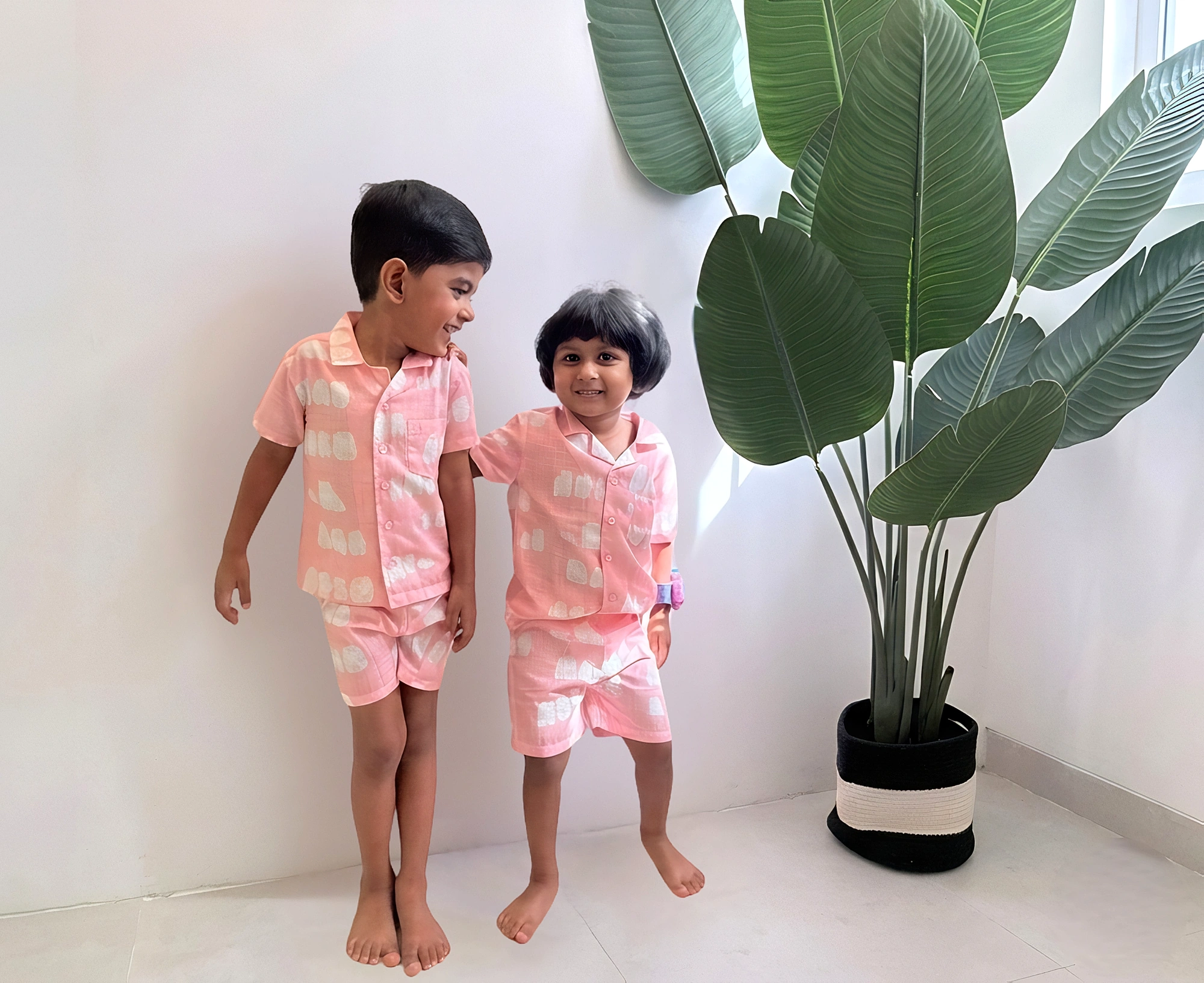 Children in colourful Tiny Tusk outfits beside a tall green plant
